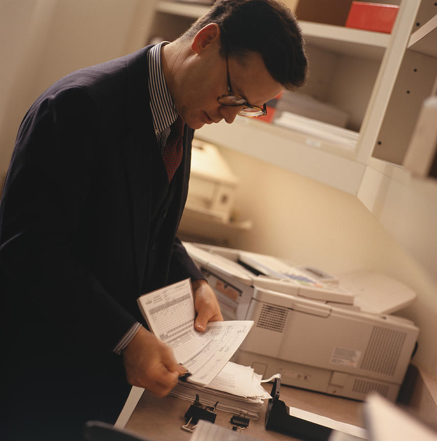Businessman using fax machine Photograph by Keith Brofsky