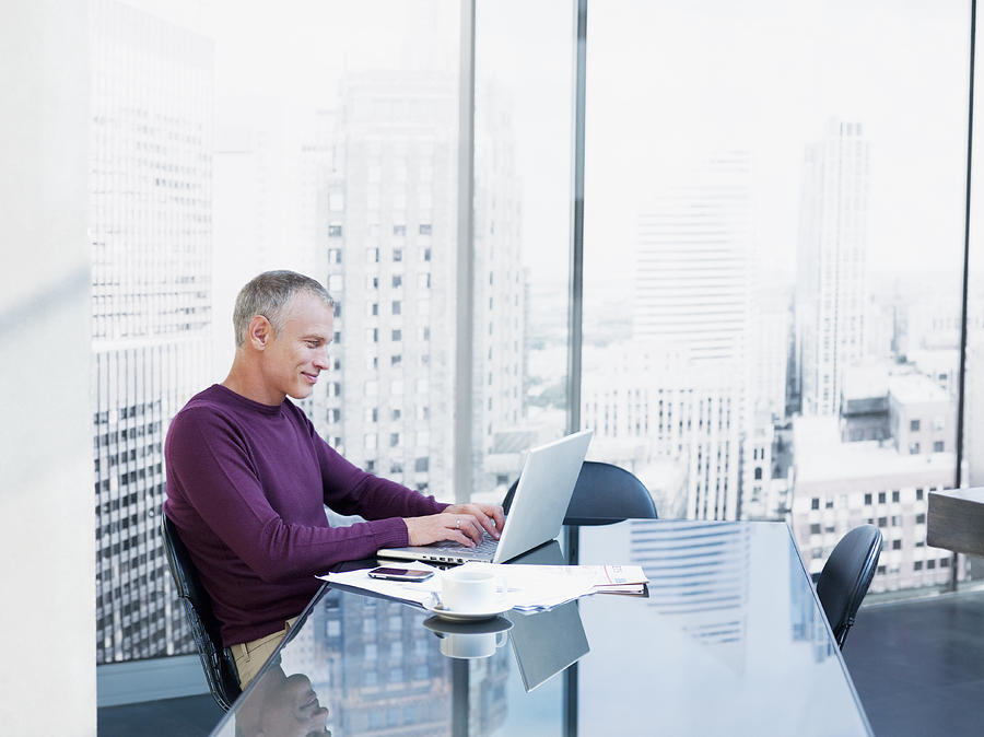 Businessman using laptop at desk Photograph by Chris Ryan