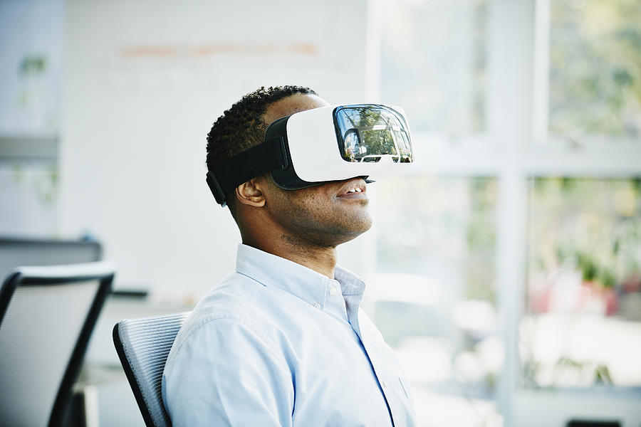 Businessman using virtual reality headset Photograph by Thomas Barwick
