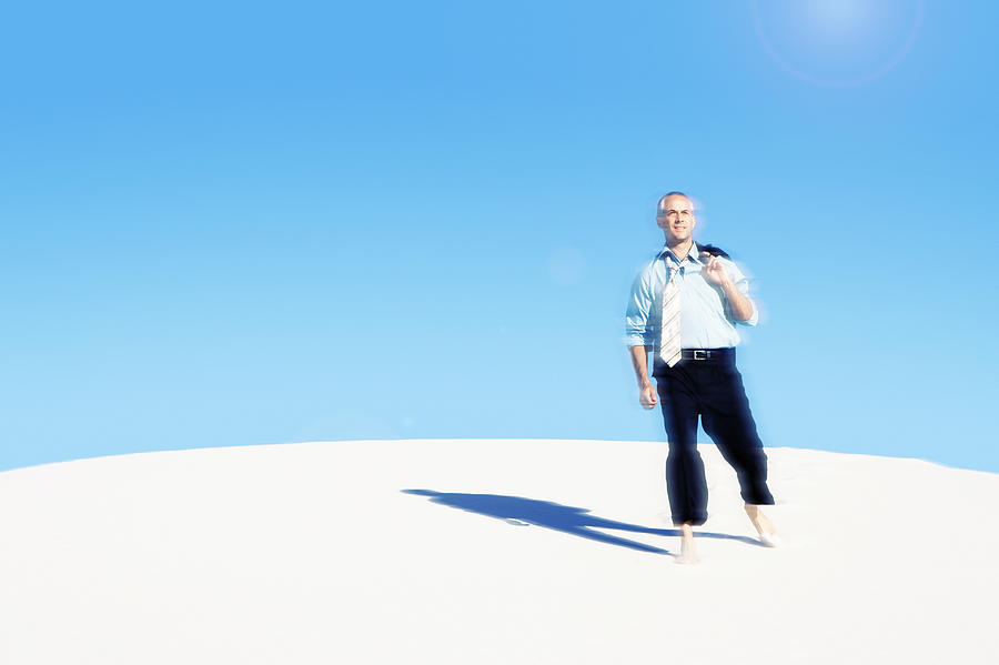 Businessman Walking Barefoot in a Desert Photograph by John Cumming