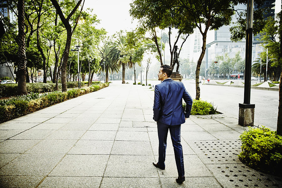 Businessman walking on sidewalk of city street Photograph by Thomas Barwick