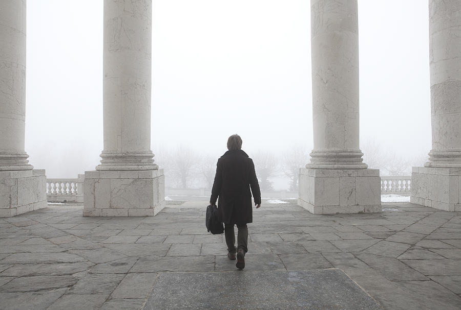 Businessman walks thru white marble columns, mist Photograph by Ascent/PKS Media Inc.