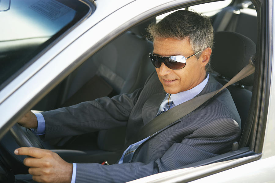 Businessman wearing shades in car, close up, elevated view Photograph by Maria Teijeiro