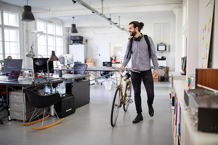 Businessman with a bicycle in office Photograph by Alvarez