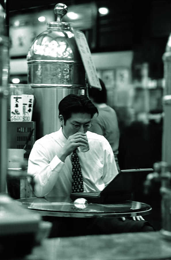 Businessman with laptop having a drink Photograph by Photodisc