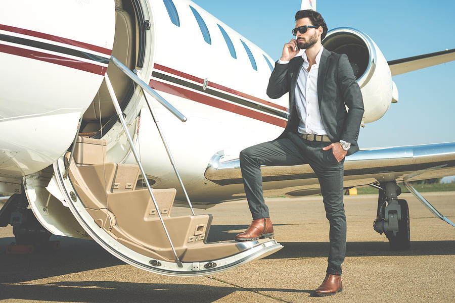 Businessman with mobile phone entering the private jet Photograph by Extreme-photographer