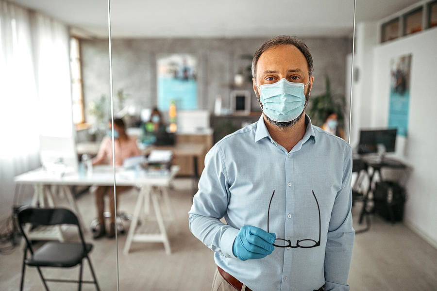 Businessman with protective gloves and face mask at office Photograph by Mixetto