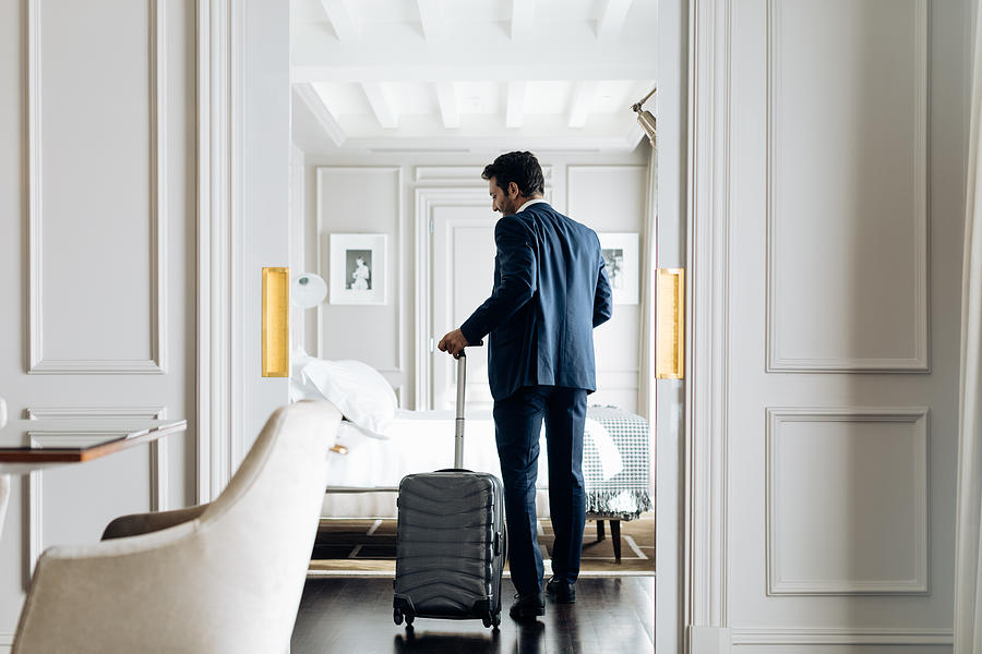 Businessman with wheeled luggage in suite Photograph by Sofie Delauw