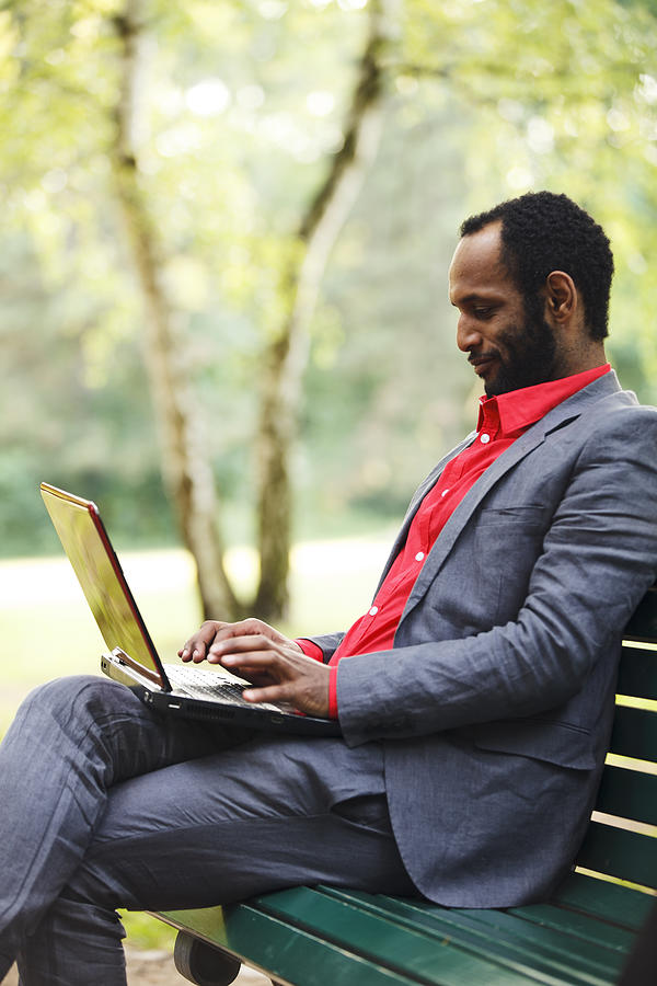 Businessman Working With Laptop In Park Photograph by Efenzi