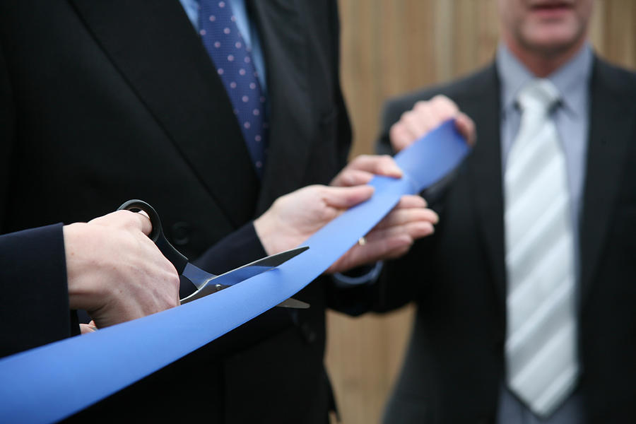 Businessmen in suits holding scissors cutting a blue ribbon Photograph by Nicholas Free