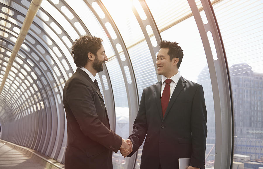Businessmen shaking hands in a futuristic tunnel Photograph by 10000 Hours