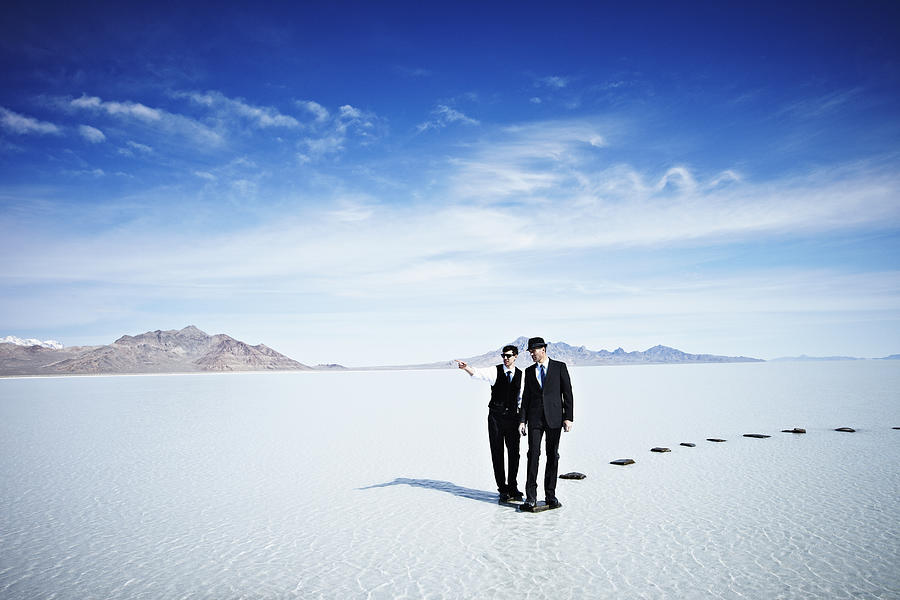 Businessmen standing at end of pathway in lake Photograph by Thomas Barwick