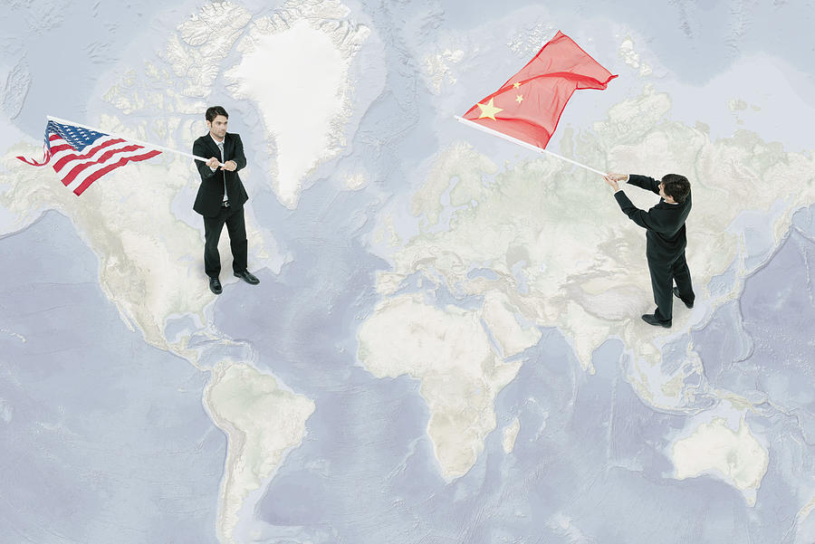 Businessmen standing on world map, waving American and Chinese flags Photograph by PhotoAlto/Milena Boniek