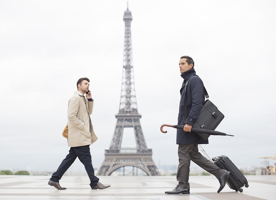 Businessmen walking past Eiffel Tower, Paris, France Photograph by Caia Image