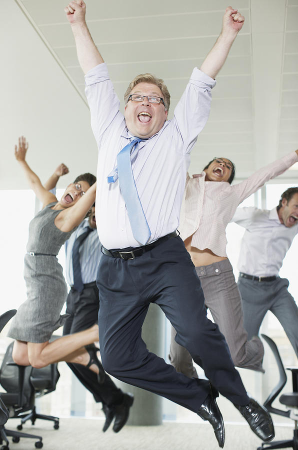 Businesspeople cheering in office Photograph by Paul Bradbury