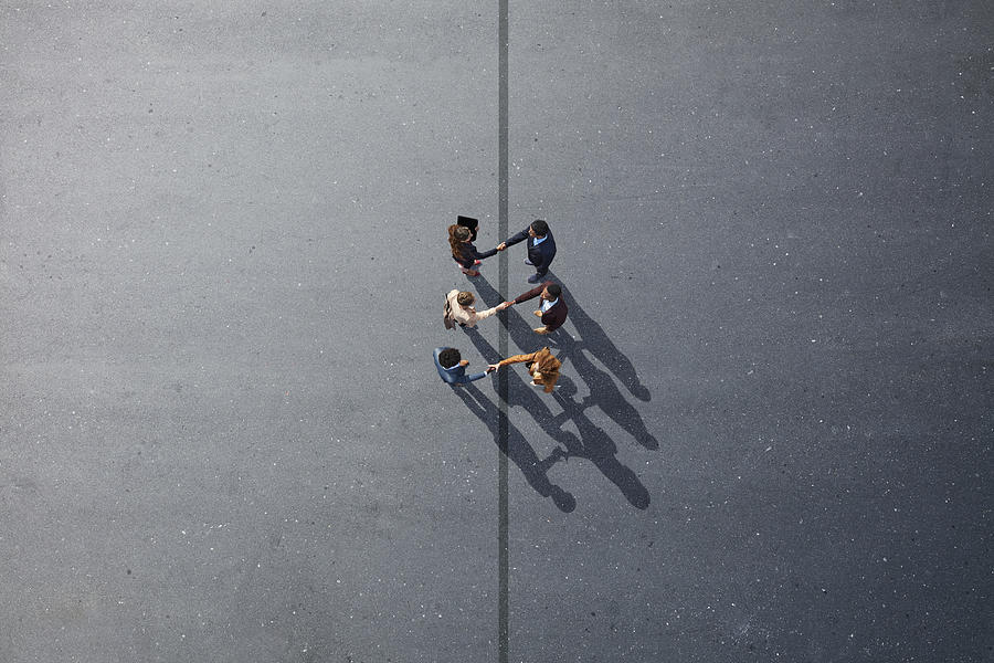 Businesspeople making handshakes across line, on painted asphalt Photograph by Klaus Vedfelt