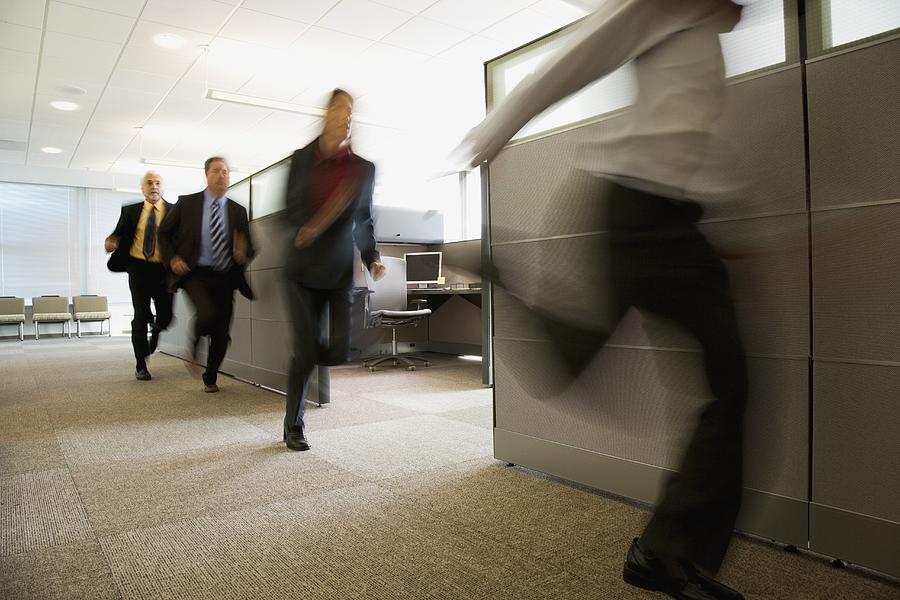 Businesspeople running past office cubicles Photograph by John M Lund Photography Inc
