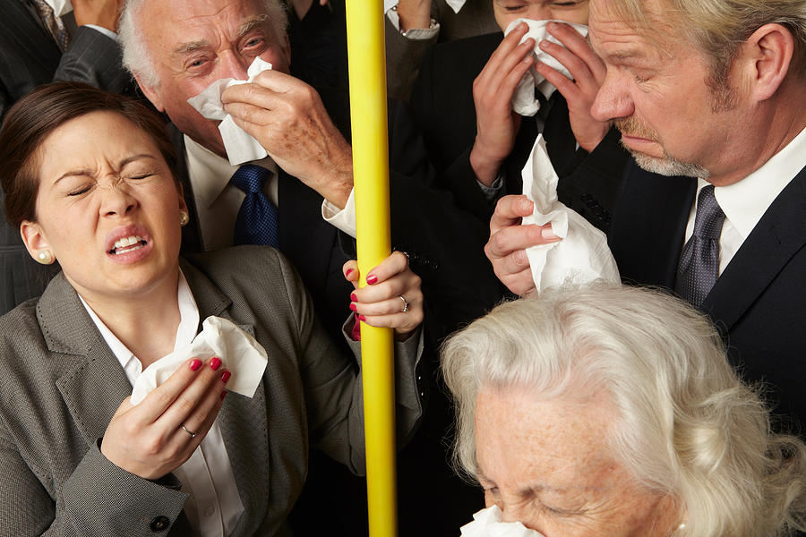 Businesspeople sneezing on subway train Photograph by Image Source