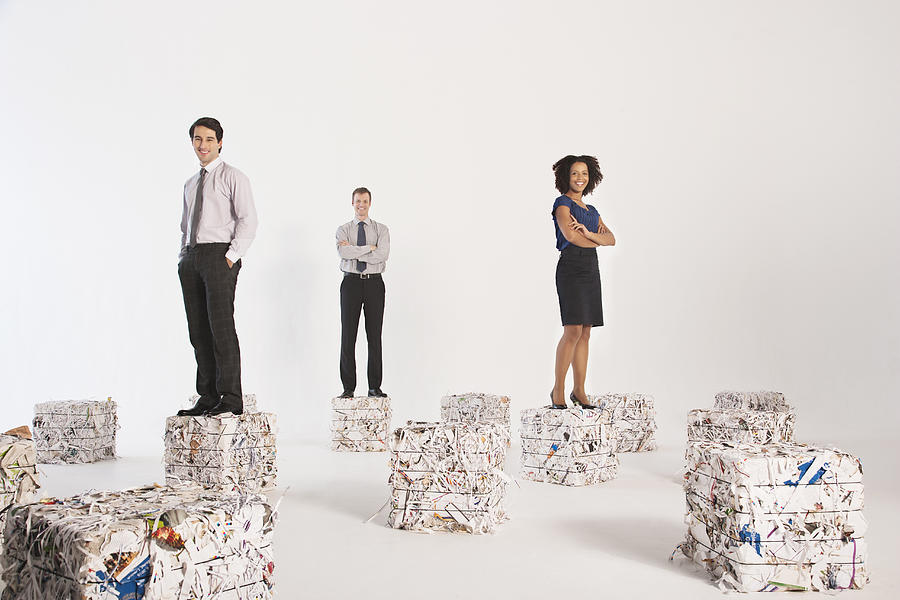 Businesspeople standing on bales of paper Photograph by Martin Barraud