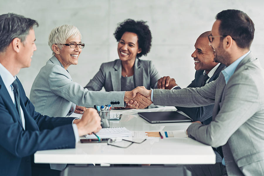 Businesswoman and businessman shaking hands across the table Photograph by Pixelfit Businesswoman and businessman shaking hands across the table Photograph by Pixelfit