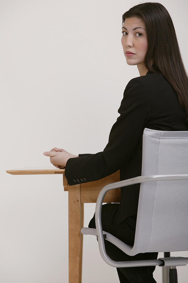 Businesswoman at desk looking over her shoulder Photograph by Comstock Images
