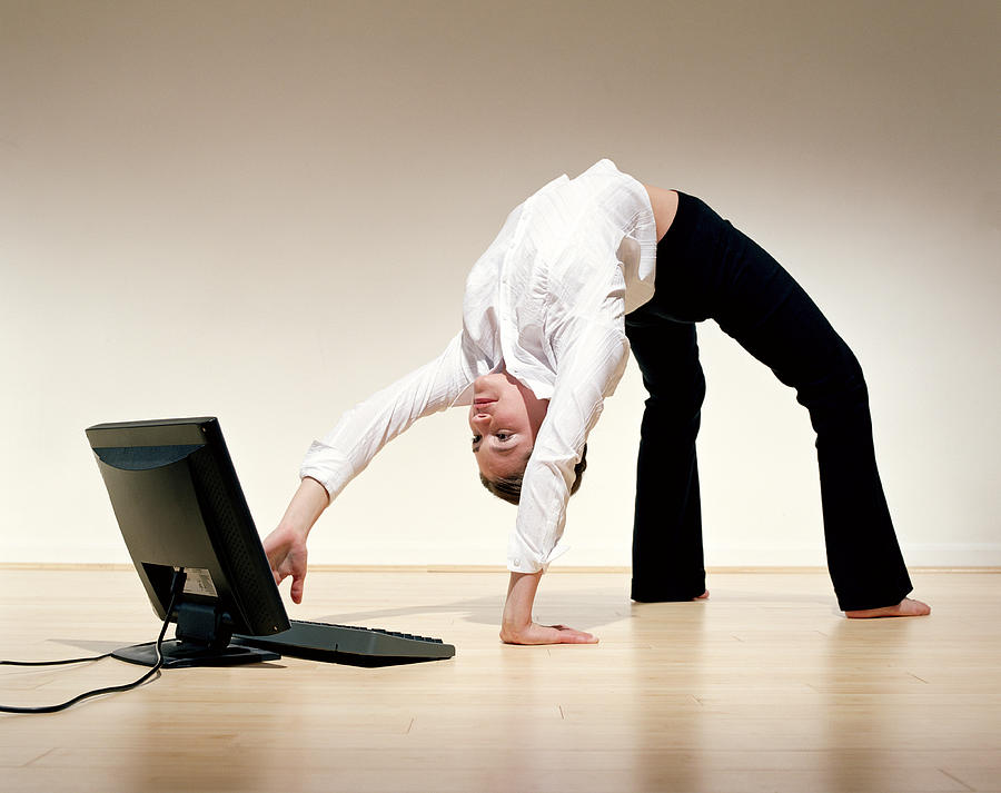 Businesswoman bent over backwards using laptop Photograph by PM Images