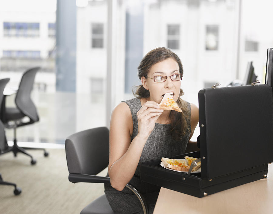 Businesswoman eating pizza from briefcase Photograph by Robert Daly