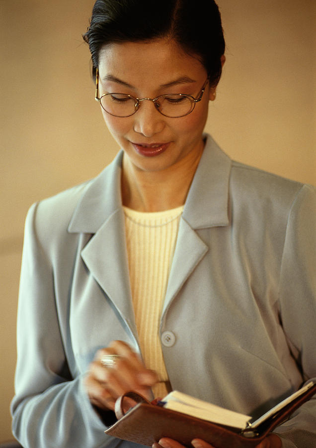 Businesswoman holding diary, portrait Photograph by Eric Audras