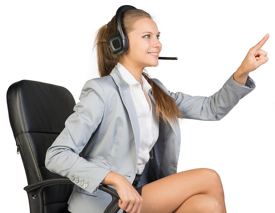 Businesswoman in headset sitting on office chair touching or pressing Photograph by Cherezoff