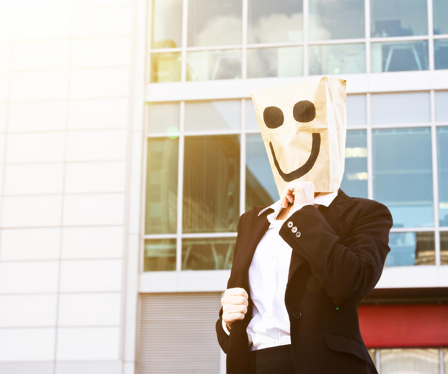 Businesswoman in smiling paper bag mask outside office building Photograph by RapidEye