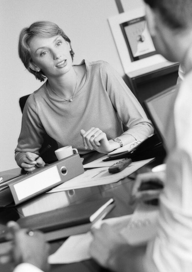 Businesswoman listening to colleague, B&W Photograph by Teo Lannie