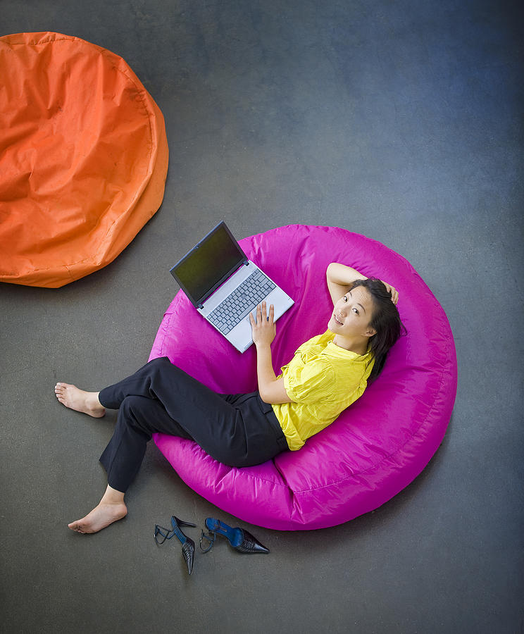 Businesswoman On Beanbag Chair With Laptop Photograph by Zia Soleil