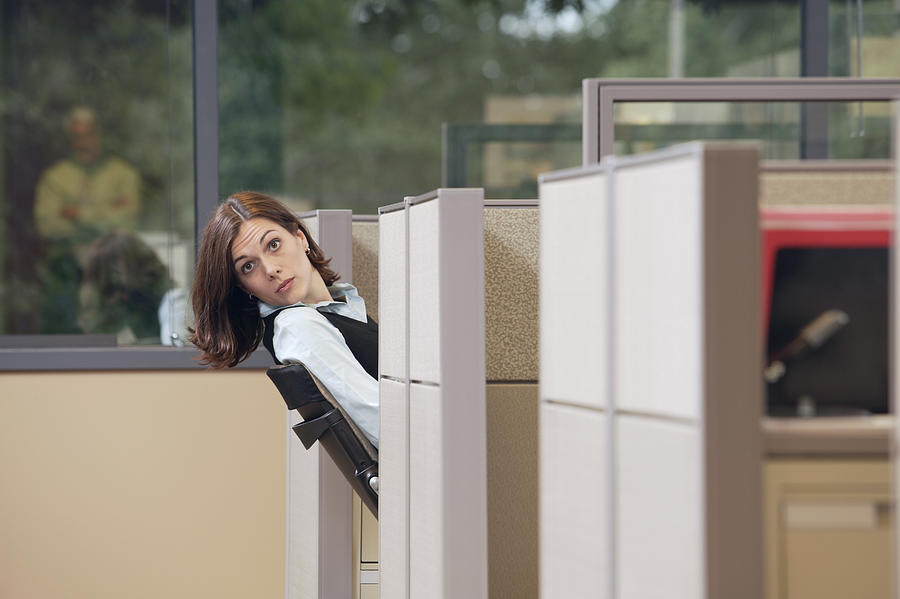 Businesswoman peeking out of cubicle Photograph by Comstock Images