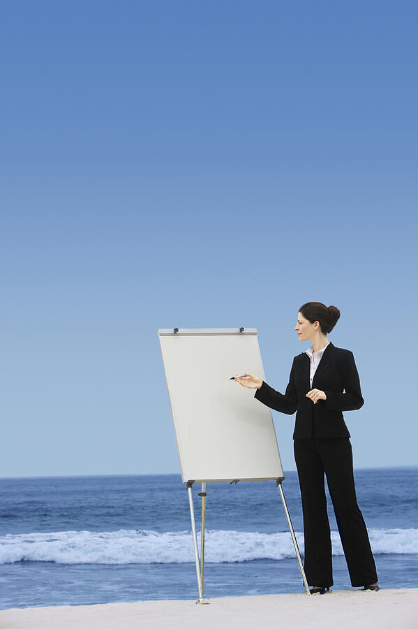 Businesswoman Pointing to a Blank Flip Chart on a Beach Photograph by John Cumming