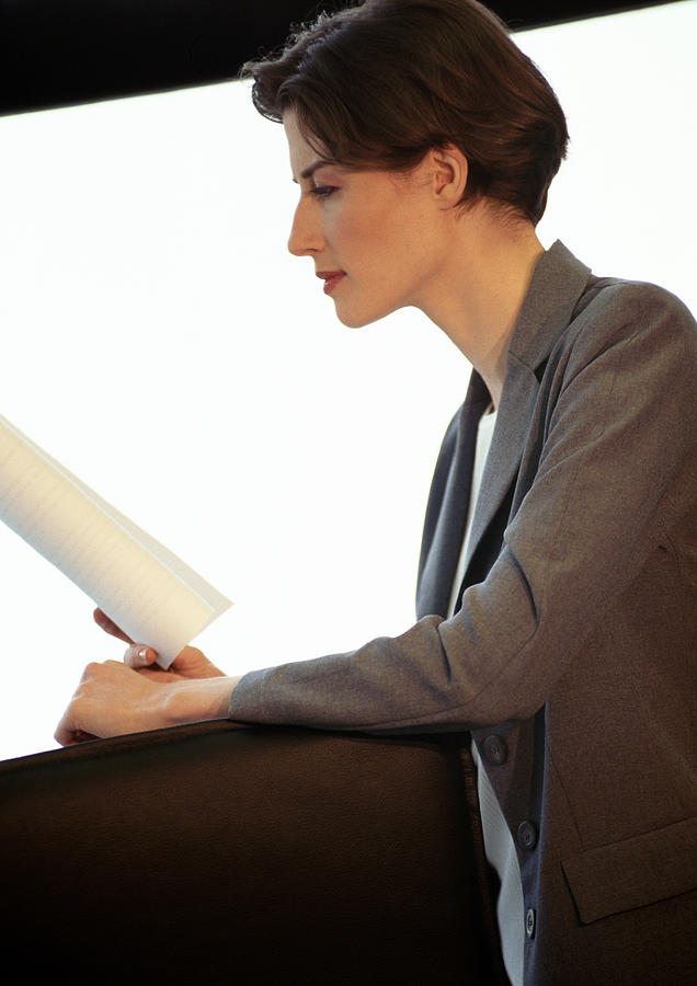 Businesswoman reading document, side view Photograph by Eric Audras