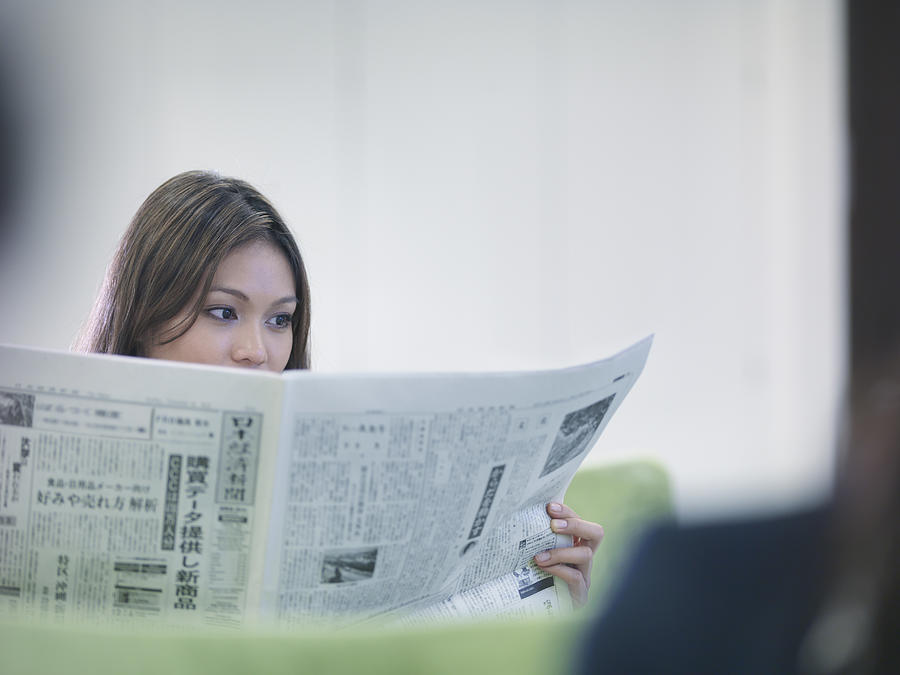 Businesswoman reading Japanese newspaper Photograph by Monty Rakusen