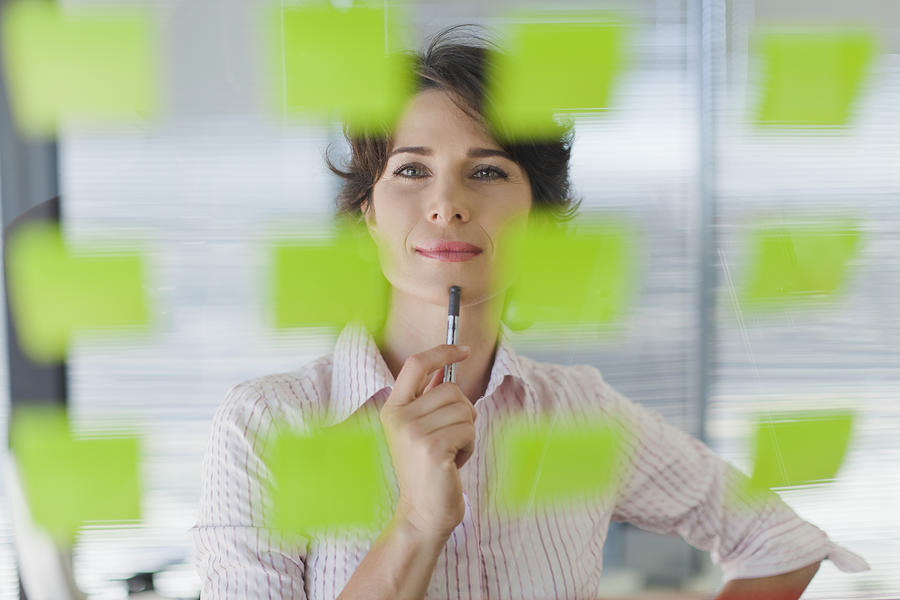 Businesswoman reading sticky notes Photograph by Hybrid Images