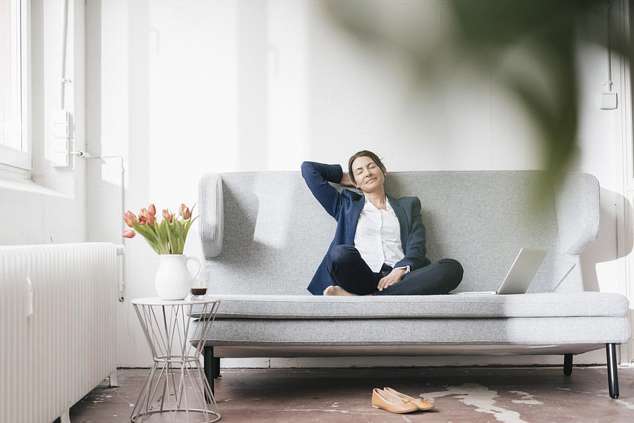 Businesswoman relaxing on couch in a loft Photograph by Westend61