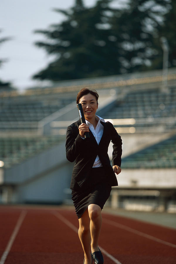 Businesswoman running relay race Photograph by Dex Image