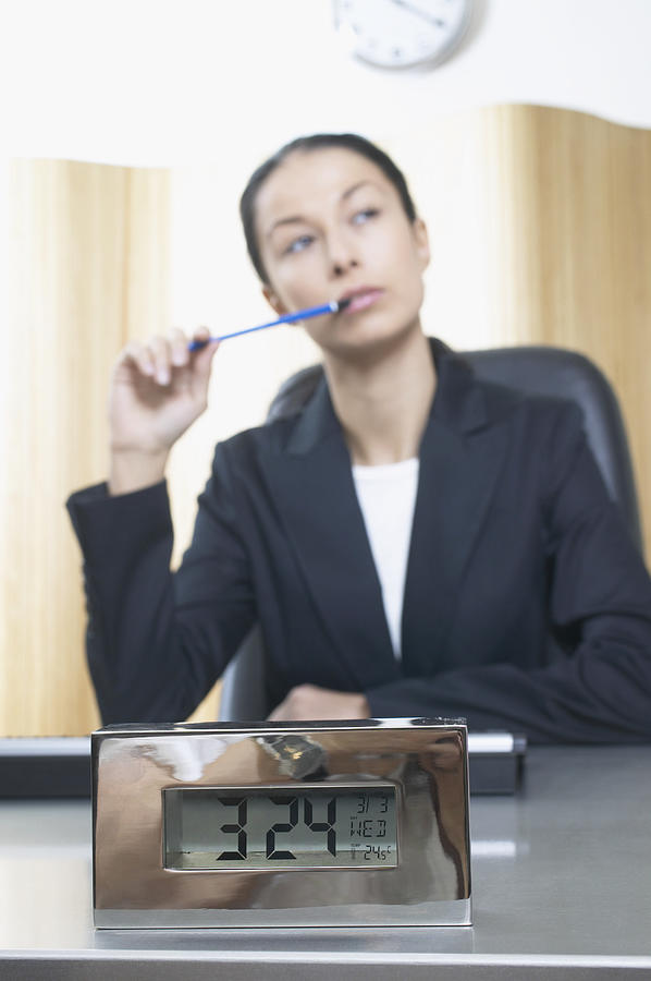 Businesswoman Sits at a Desk Thinking, Focus on Alarm Clock Photograph by B2M Productions