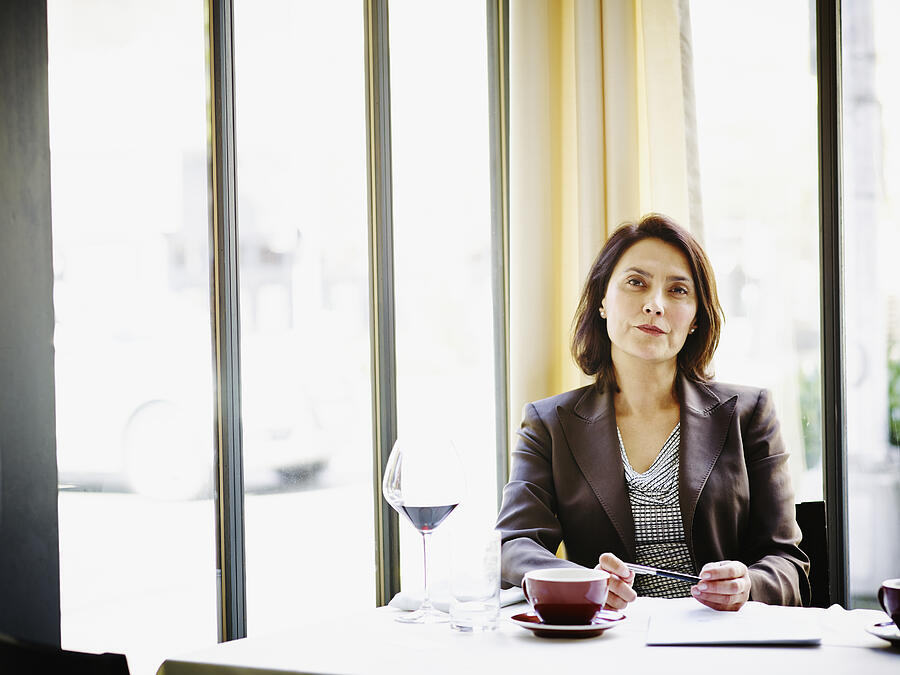 Businesswoman sitting at table in restaurant Photograph by Thomas Barwick