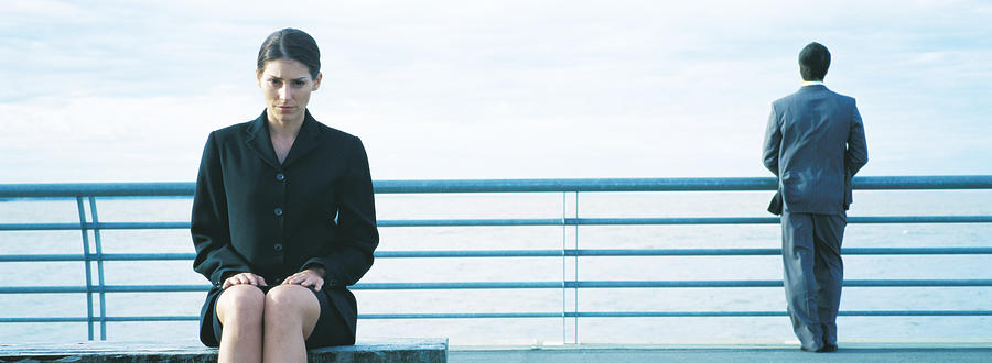 Businesswoman sitting, businessman standing at railing in background, panoramic Photograph by Matthieu Spohn