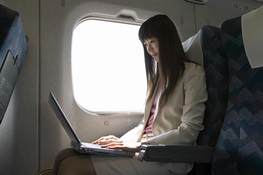 Businesswoman Sitting in a Passenger Train and Using a Laptop Photograph by Digital Vision.