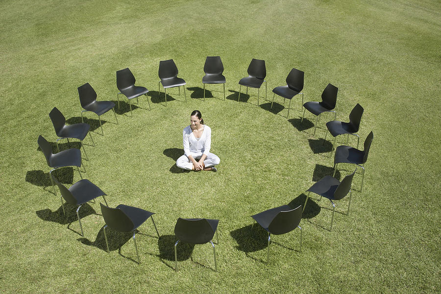 Businesswoman sitting in circle of office chairs in field Photograph by Martin Barraud