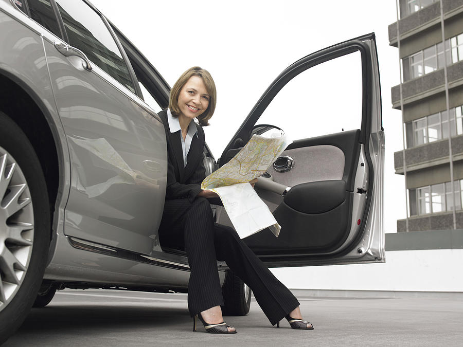 Businesswoman Sitting in Her Car With a Map Photograph by Digital Vision.