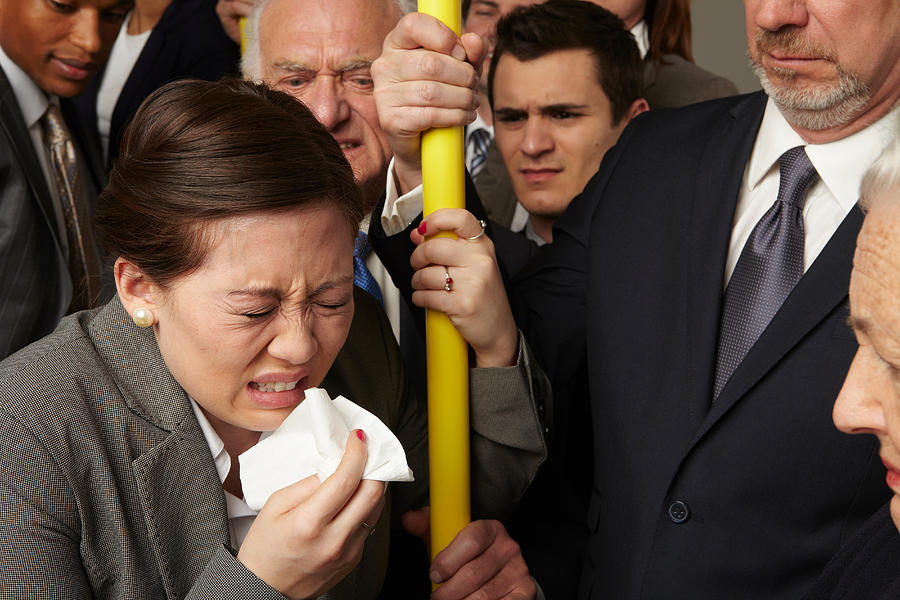 Businesswoman sneezing on subway train Photograph by Image Source