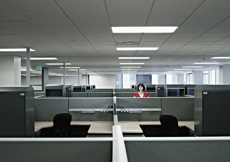 Businesswoman standing alone in empty office Photograph by Thomas Barwick