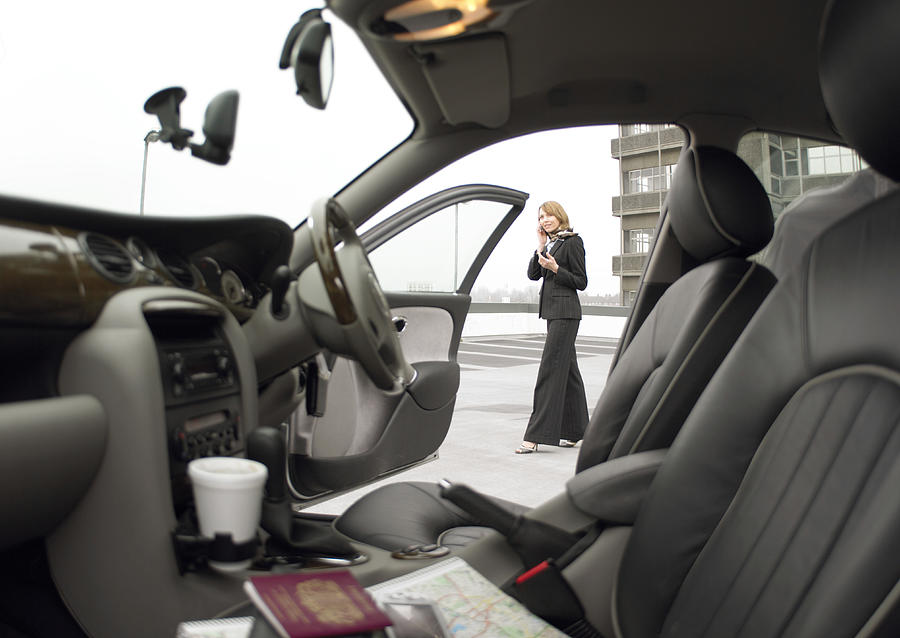 Businesswoman Standing by Her Car and Using a Mobile Phone Photograph by Digital Vision.
