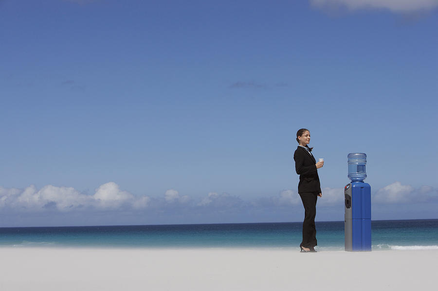 Businesswoman Standing Next to a Water Cooler Photograph by Digital Vision.