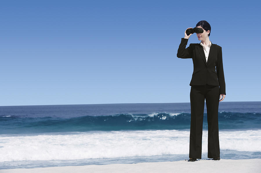 Businesswoman Standing on a Beach Looking Through Binoculars Photograph by John Cumming